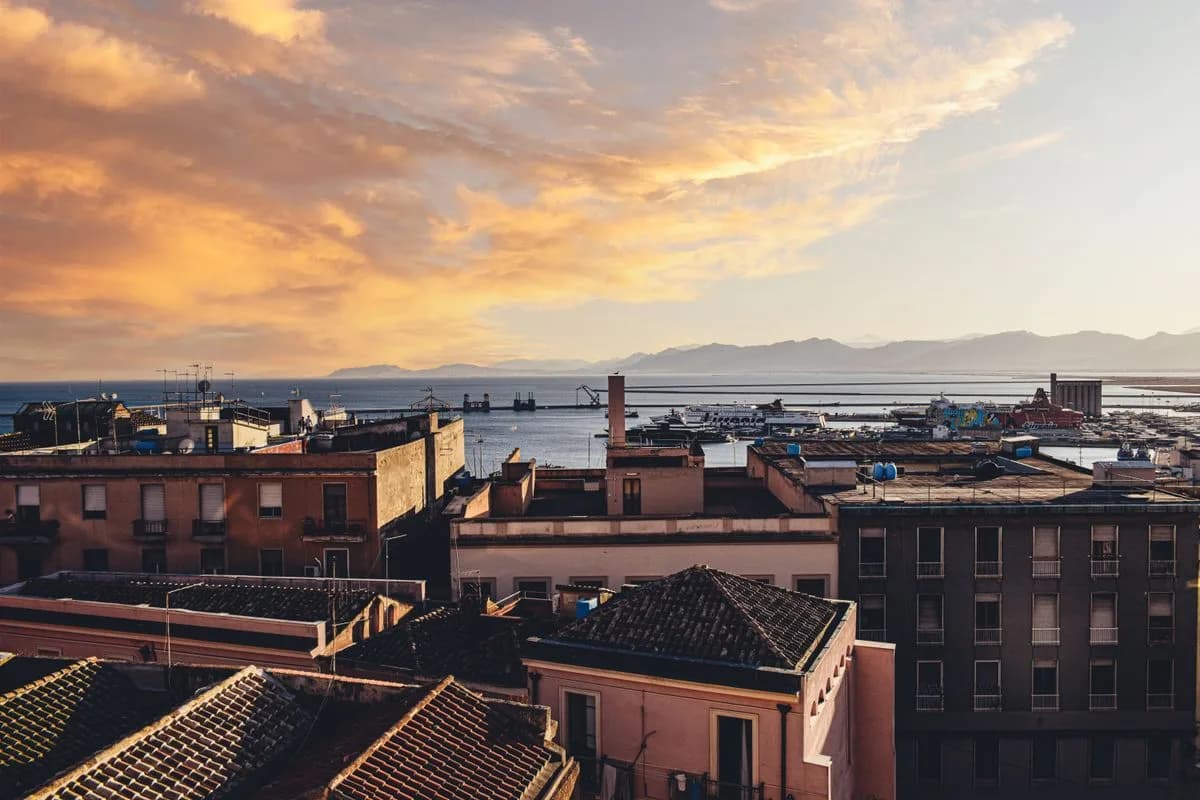 Tetti e porto di Cagliari sotto un cielo dorato al tramonto
