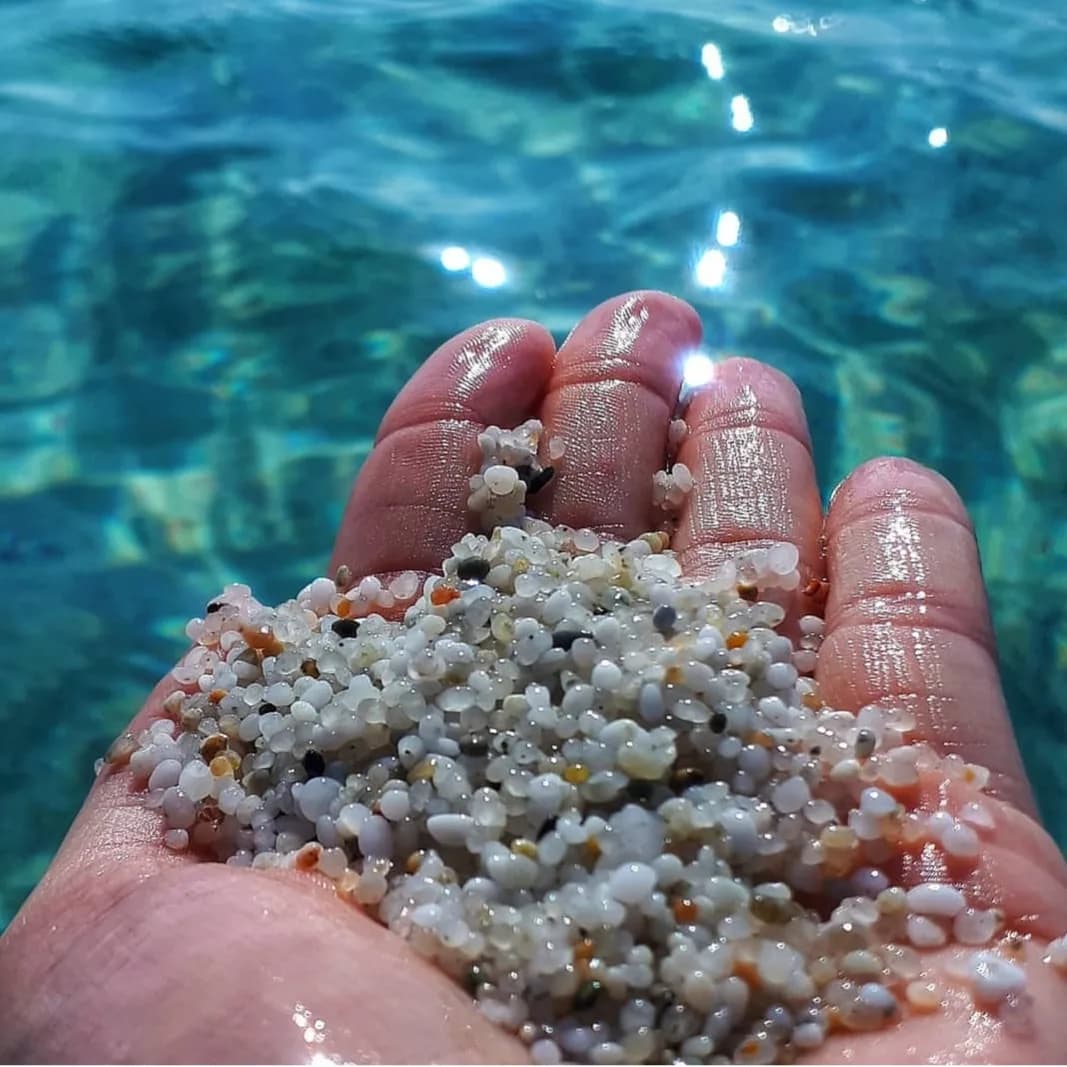 Dettaglio di granelli di quarzo accanto all’acqua limpida di Is Arutas