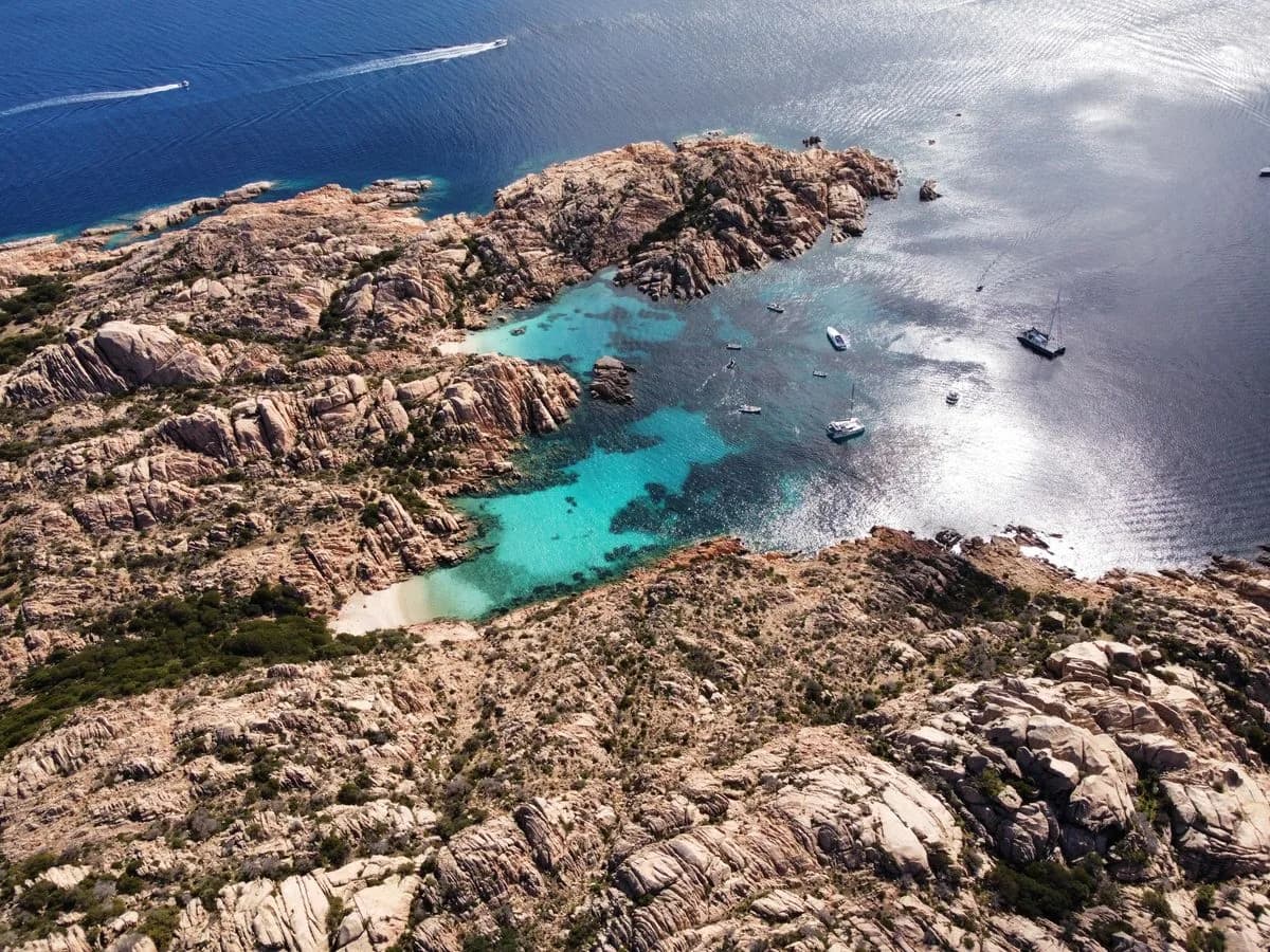 Barche in cale azzurre tra le isole di granito di La Maddalena